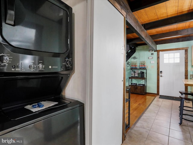 laundry area with light tile patterned floors, stacked washer and dryer, and wooden ceiling