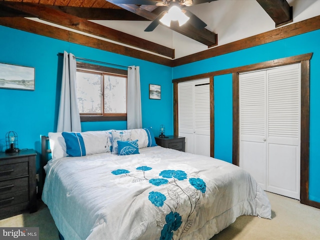 bedroom featuring light carpet, lofted ceiling with beams, two closets, and ceiling fan