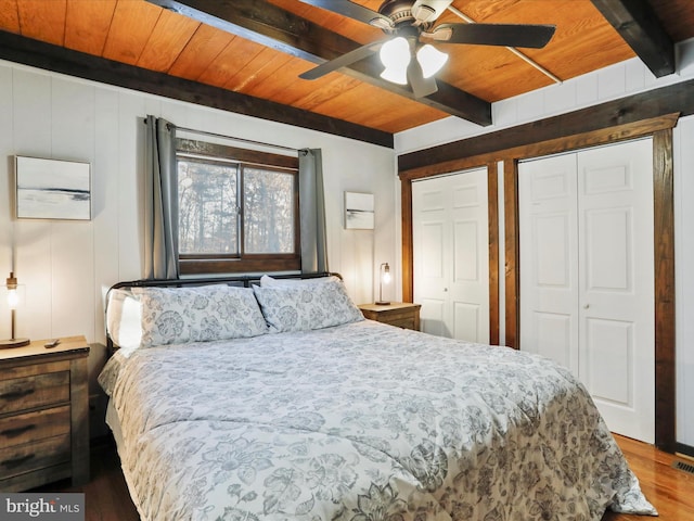 bedroom featuring hardwood / wood-style flooring, ceiling fan, wooden ceiling, and multiple closets