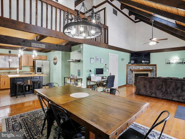 dining space with beamed ceiling, ceiling fan, high vaulted ceiling, and light hardwood / wood-style flooring