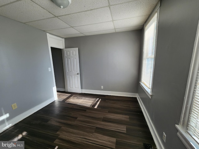 spare room featuring a drop ceiling and dark wood-type flooring