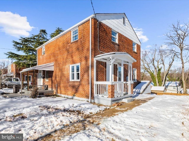 snow covered property with covered porch