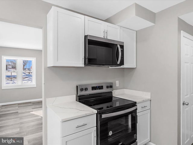 kitchen featuring stainless steel appliances, white cabinetry, light hardwood / wood-style floors, and light stone counters