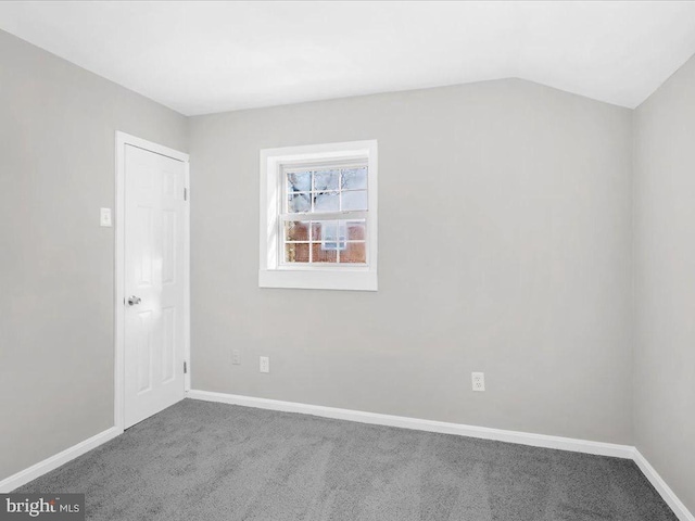 carpeted spare room with lofted ceiling