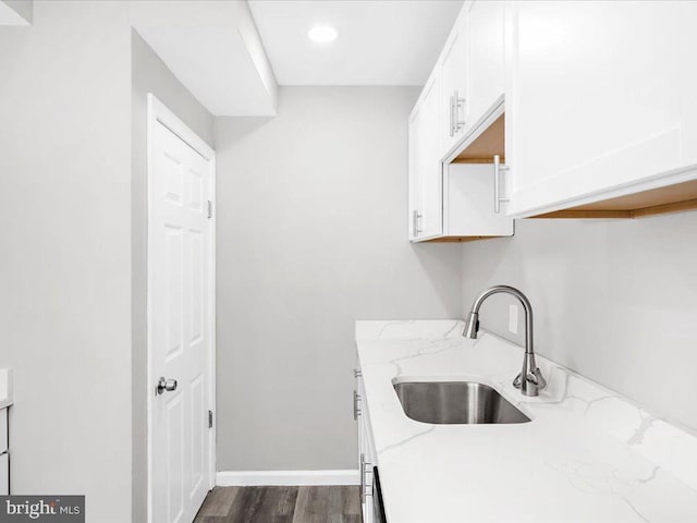 kitchen with dark hardwood / wood-style flooring, white cabinetry, sink, and light stone countertops