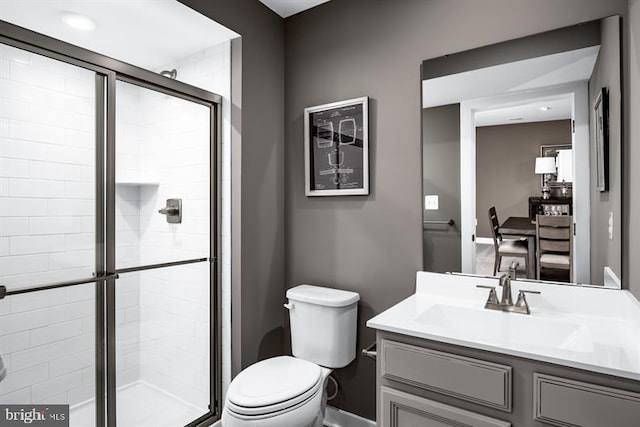 bathroom with a shower with door, vanity, and toilet