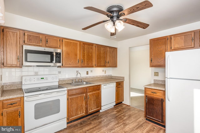 kitchen with ceiling fan, dark hardwood / wood-style floors, tasteful backsplash, white appliances, and sink