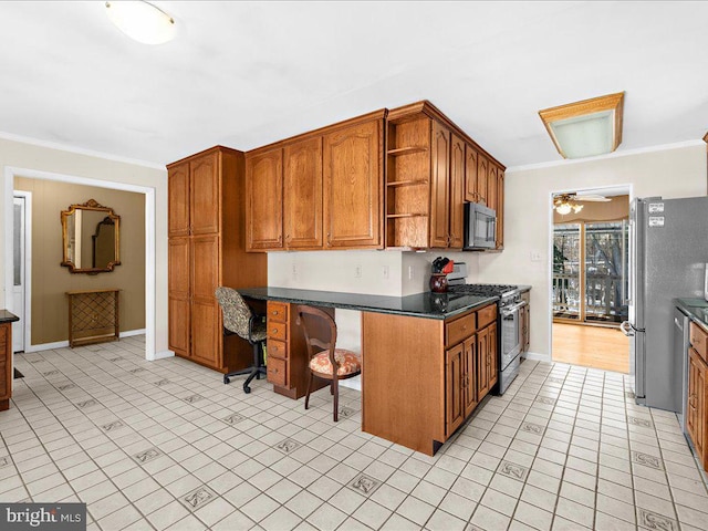 kitchen with a breakfast bar, crown molding, ceiling fan, built in desk, and appliances with stainless steel finishes