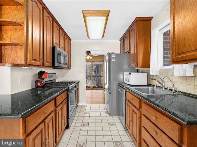 kitchen featuring stainless steel appliances, ceiling fan, sink, dark stone countertops, and light tile patterned flooring