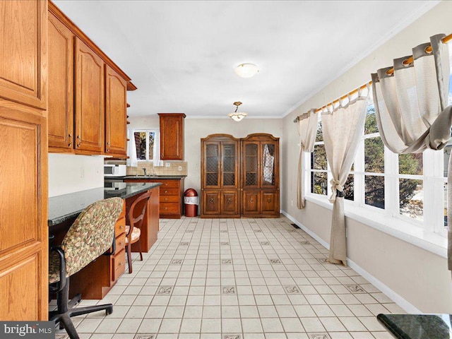 kitchen with backsplash, dark stone countertops, sink, and ornamental molding