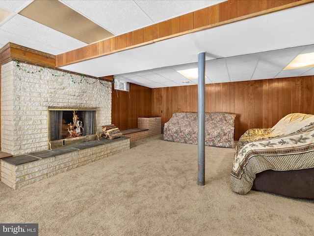 basement with wood walls, a fireplace, and carpet