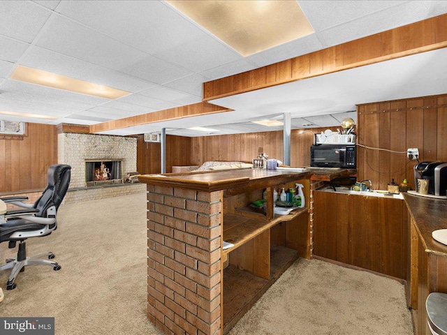 interior space with a paneled ceiling, a fireplace, light carpet, and wooden walls