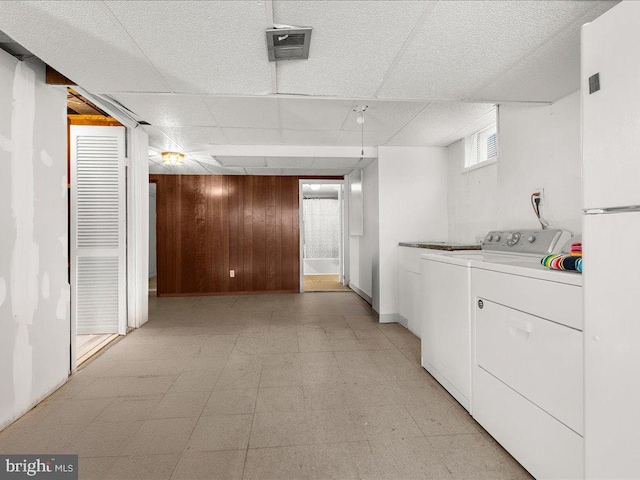 clothes washing area featuring separate washer and dryer and wooden walls