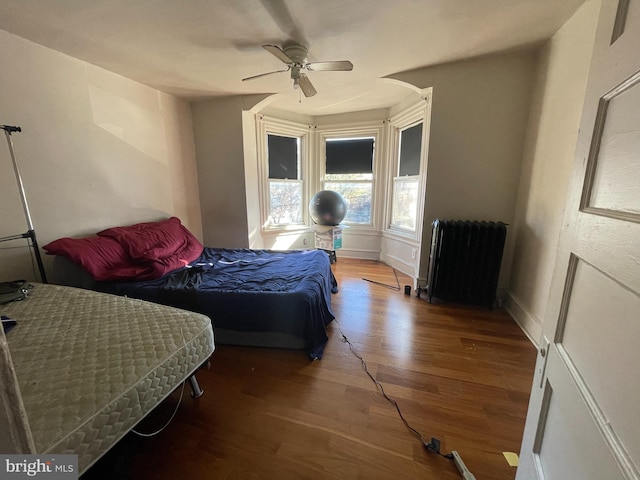 bedroom with hardwood / wood-style flooring, radiator, and ceiling fan