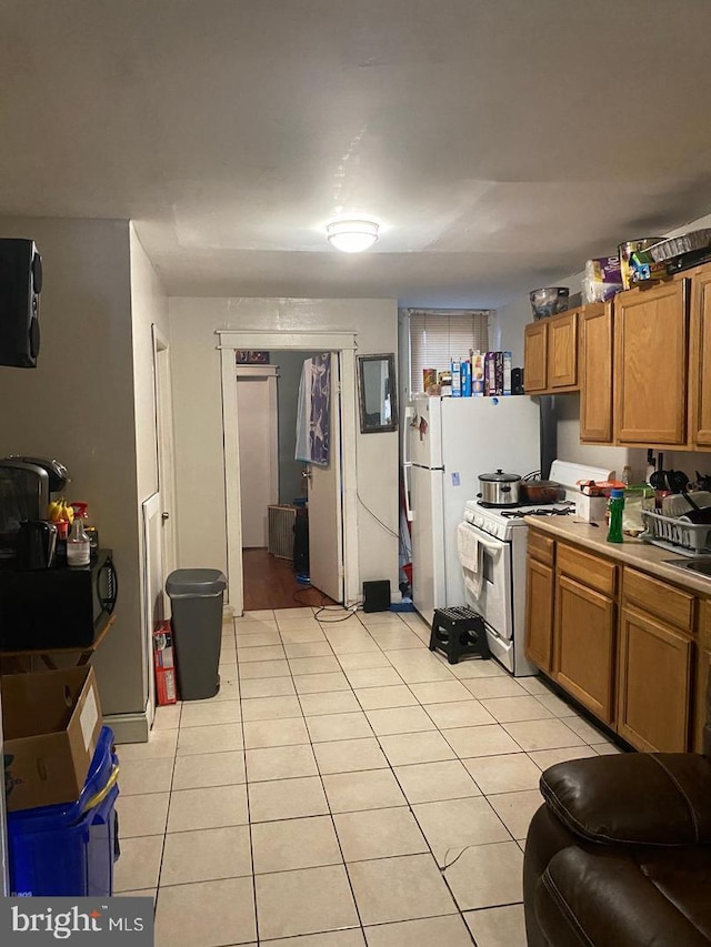 kitchen featuring light tile patterned flooring and white appliances