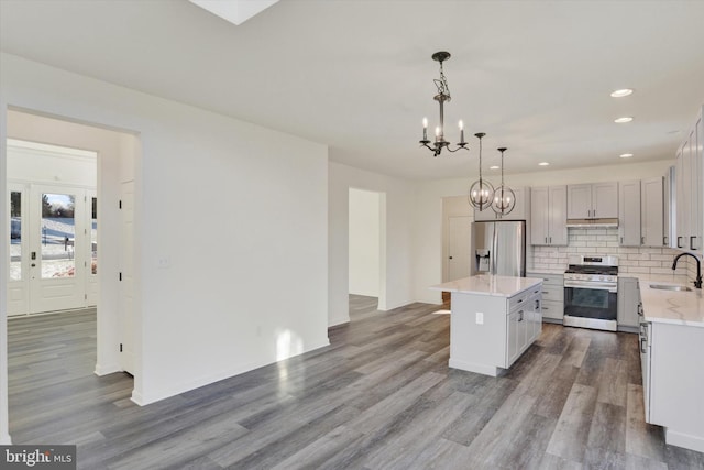 kitchen featuring pendant lighting, sink, decorative backsplash, a kitchen island, and stainless steel appliances