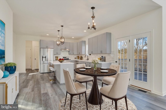 dining area with wood-type flooring, sink, and an inviting chandelier