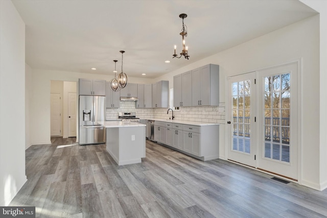 kitchen featuring gray cabinets, a kitchen island, pendant lighting, and appliances with stainless steel finishes