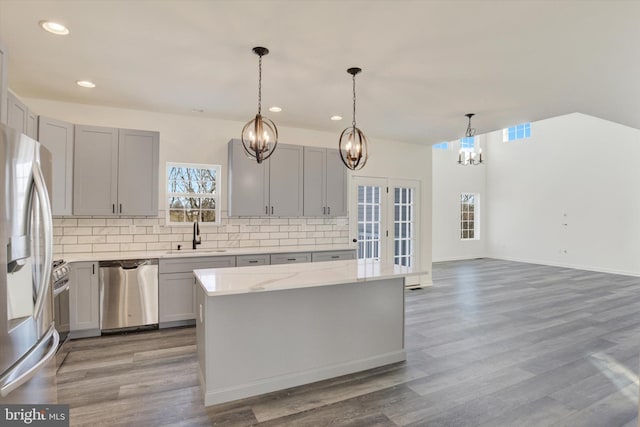 kitchen featuring french doors, sink, light stone countertops, decorative light fixtures, and stainless steel appliances