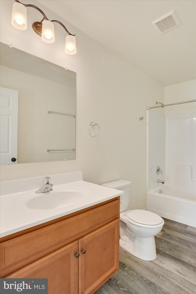 full bathroom with vanity, hardwood / wood-style floors,  shower combination, and toilet