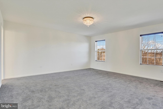 empty room with carpet, plenty of natural light, and a notable chandelier