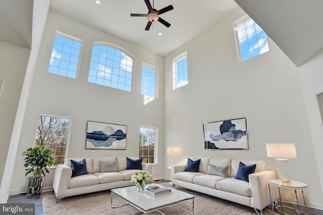 living room featuring hardwood / wood-style floors, ceiling fan, and a towering ceiling