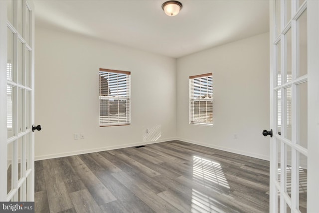 spare room featuring french doors and dark hardwood / wood-style floors