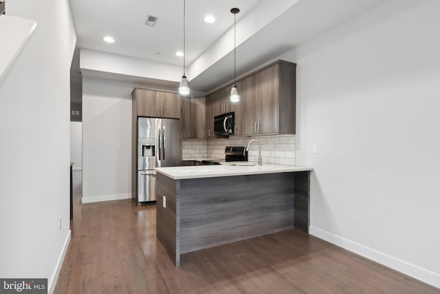 kitchen with sink, hanging light fixtures, backsplash, kitchen peninsula, and appliances with stainless steel finishes