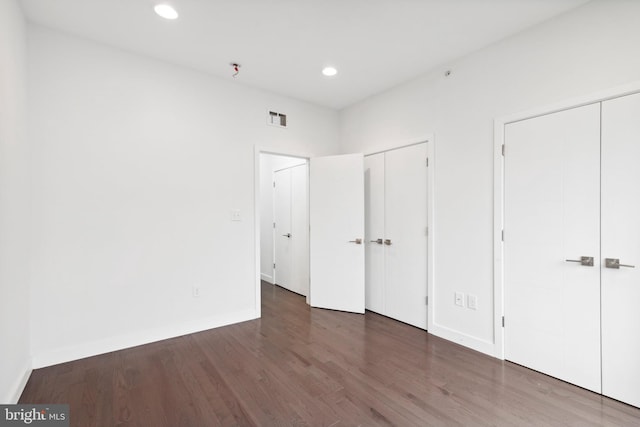 unfurnished bedroom featuring dark hardwood / wood-style flooring and two closets