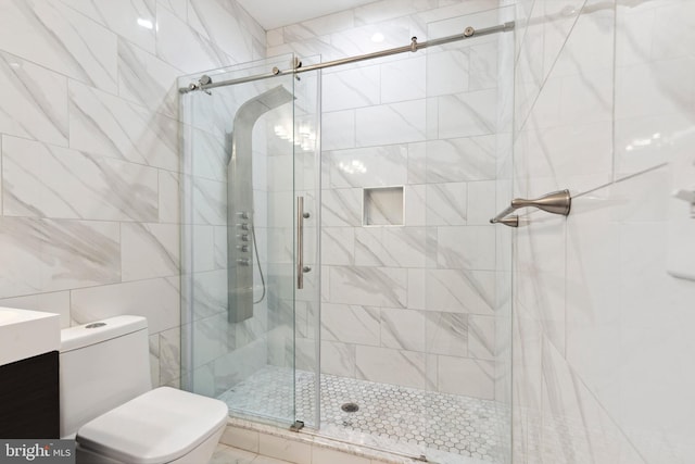 bathroom featuring vanity, toilet, a shower with door, and tile walls