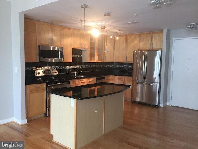 kitchen with sink, wood-type flooring, light brown cabinetry, a kitchen island, and appliances with stainless steel finishes