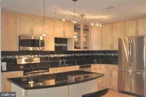 kitchen with decorative backsplash, dark countertops, glass insert cabinets, appliances with stainless steel finishes, and a center island