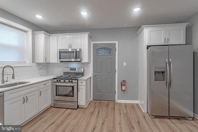 kitchen featuring decorative backsplash, stainless steel appliances, white cabinetry, and sink