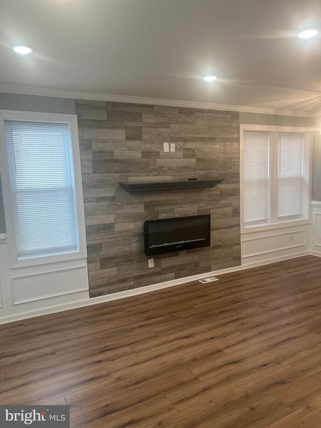 unfurnished living room featuring crown molding, dark hardwood / wood-style flooring, and a fireplace