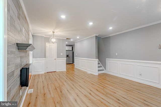 unfurnished living room with a tiled fireplace, crown molding, and light hardwood / wood-style flooring