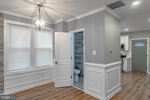 interior space with stainless steel appliances, white cabinetry, a notable chandelier, and light hardwood / wood-style flooring