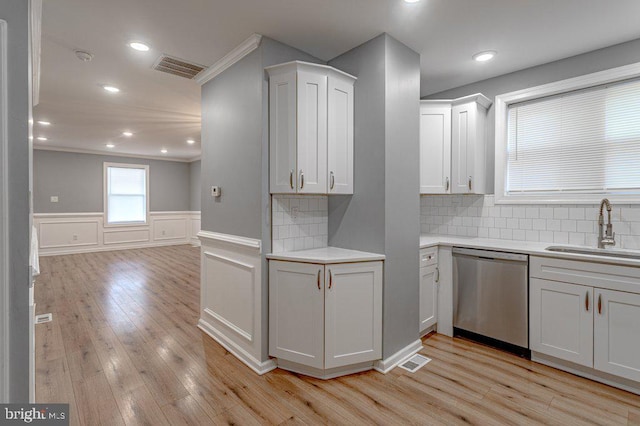 kitchen with decorative backsplash, stainless steel dishwasher, sink, light hardwood / wood-style flooring, and white cabinetry