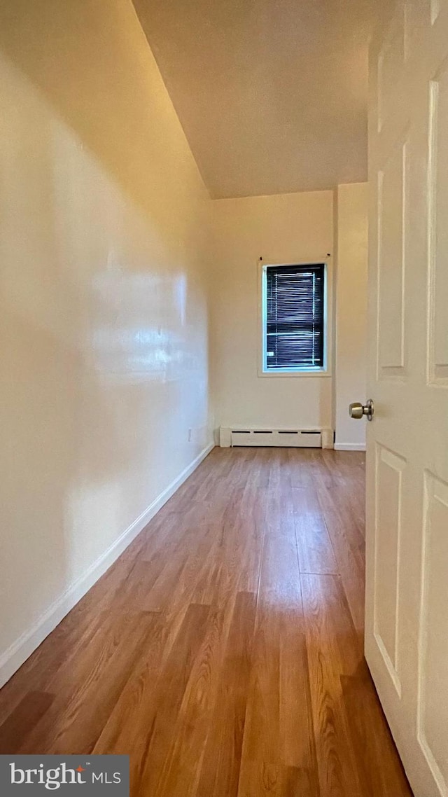 interior space with lofted ceiling, a baseboard radiator, and hardwood / wood-style floors