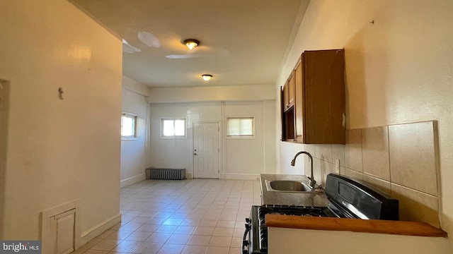 kitchen featuring sink, radiator, black stove, and light tile patterned floors