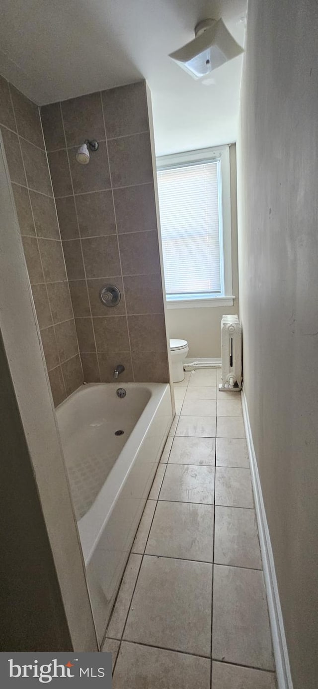 bathroom featuring tile patterned floors, toilet, and tiled shower / bath combo