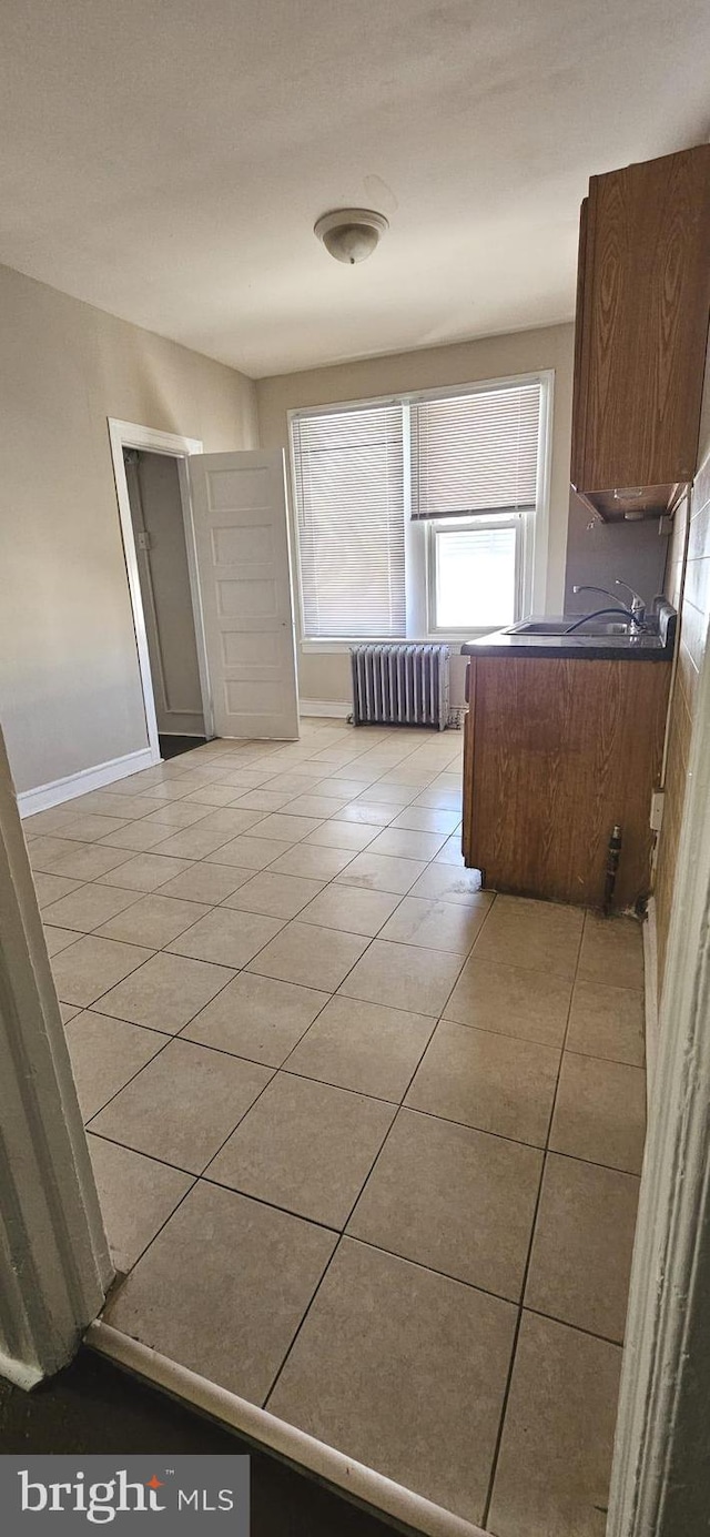 interior space featuring radiator, sink, and light tile patterned flooring