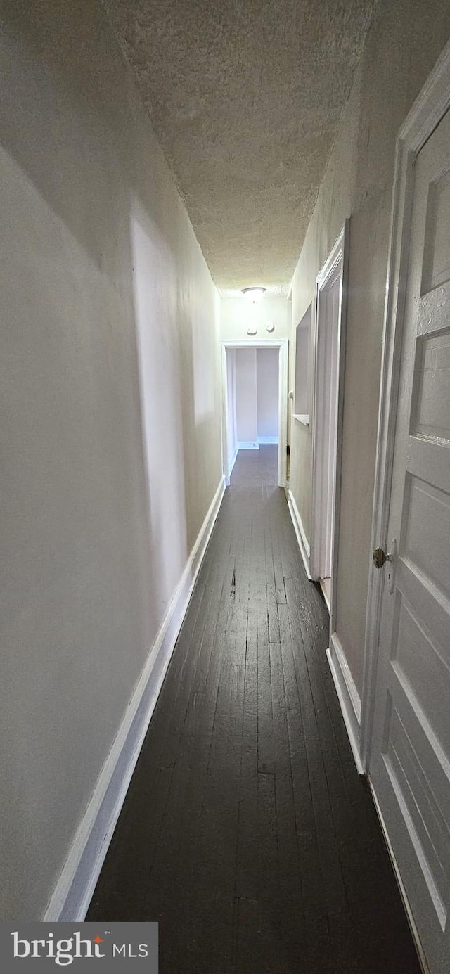 hall featuring a textured ceiling and dark hardwood / wood-style flooring