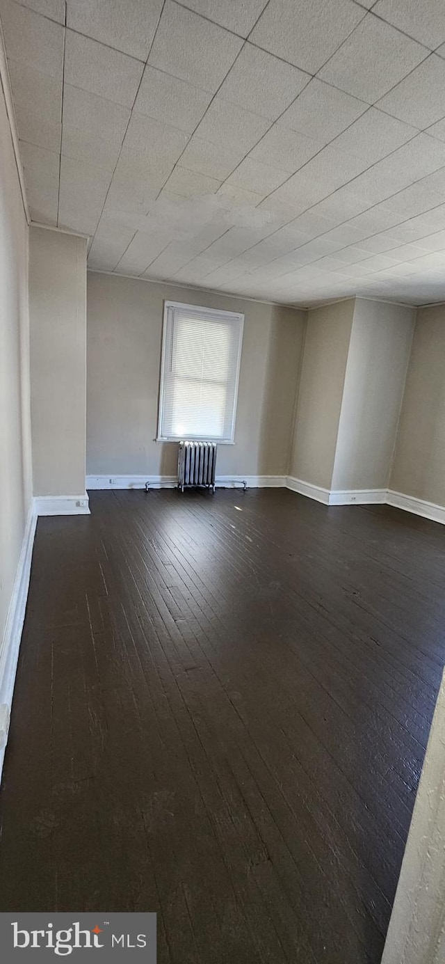 empty room featuring radiator and dark wood-type flooring