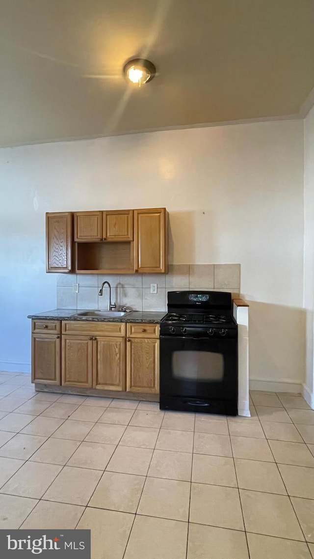 kitchen featuring sink, black gas range, tasteful backsplash, and light tile patterned floors