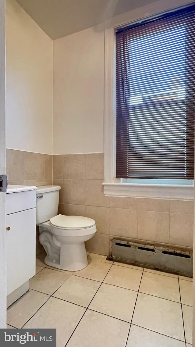 bathroom with tile patterned floors, tile walls, and toilet