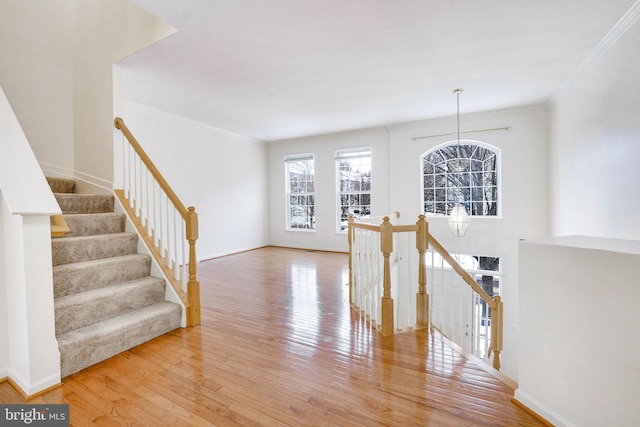 staircase with hardwood / wood-style flooring, crown molding, and an inviting chandelier