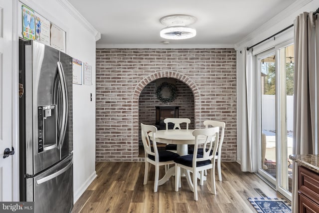 dining room with hardwood / wood-style flooring, ornamental molding, and brick wall