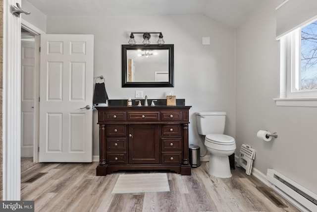 bathroom featuring vanity, vaulted ceiling, hardwood / wood-style flooring, toilet, and a baseboard radiator