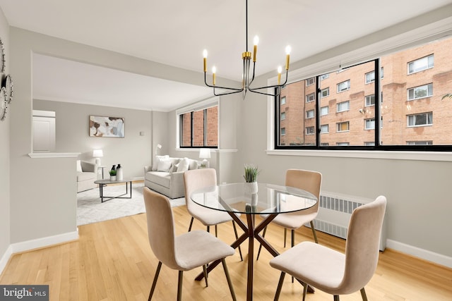 dining room featuring radiator heating unit, a notable chandelier, and light wood-type flooring