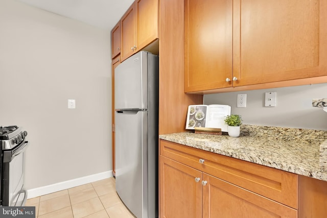 kitchen with light stone countertops, stainless steel appliances, and light tile patterned flooring